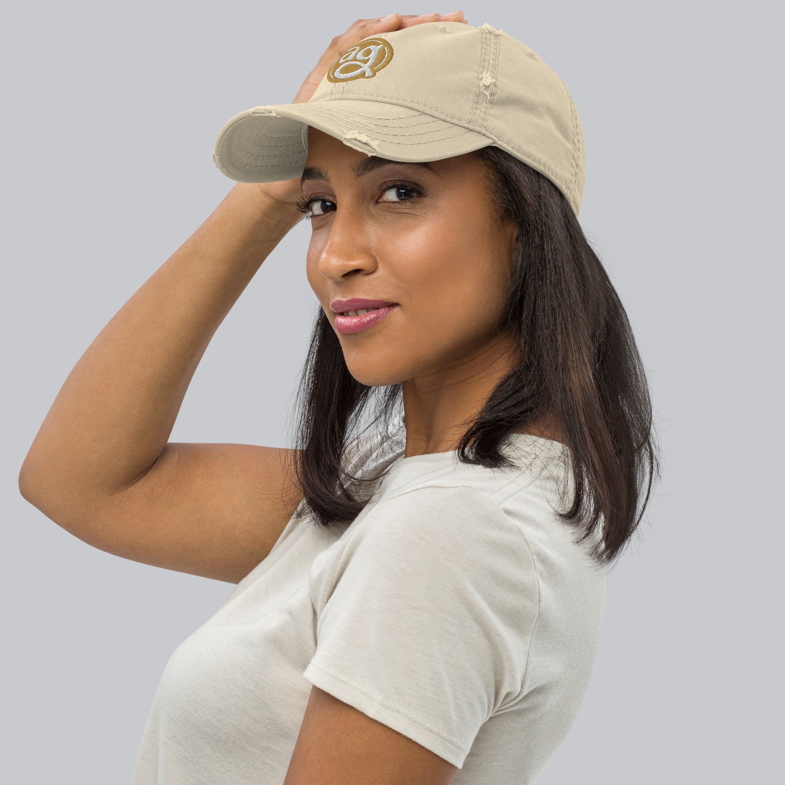 AG - Woman wearing a beige cap and white shirt on a gray background