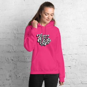 AG - Woman wearing a heliconia hoodie with, know your worth, text against a white brick wall.