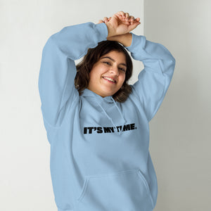 AG - Woman wearing a light blue hoodie with 'IT'S MY TIME' text, smiling against a plain background