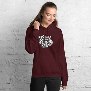 AG - Woman wearing a maroon hoodie with, know your worth, text against a white brick wall.