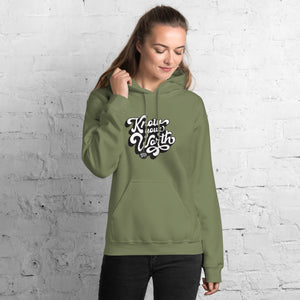 AG - Woman wearing a military green hoodie with, know your worth, text against a white brick wall.
