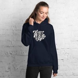 AG - Woman wearing a navy hoodie with, know your worth, text against a white brick wall.