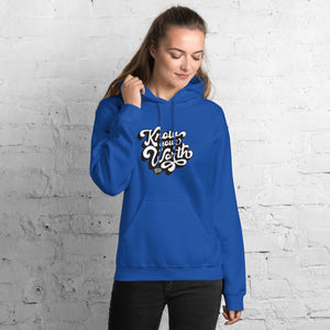 AG - Woman wearing a royal hoodie with, know your worth, text against a white brick wall.