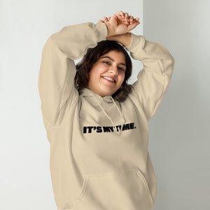 AG - Woman wearing a sand hoodie with 'IT'S MY TIME' text, smiling against a plain background