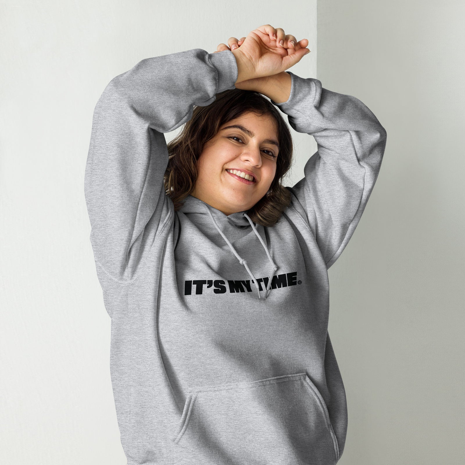 AG - Woman wearing a gray hoodie with 'IT'S MY TIME' text, smiling against a plain background