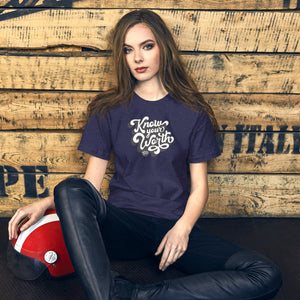 AG - Woman wearing a midnight navy with know your worth text, sitting against a wooden wall.