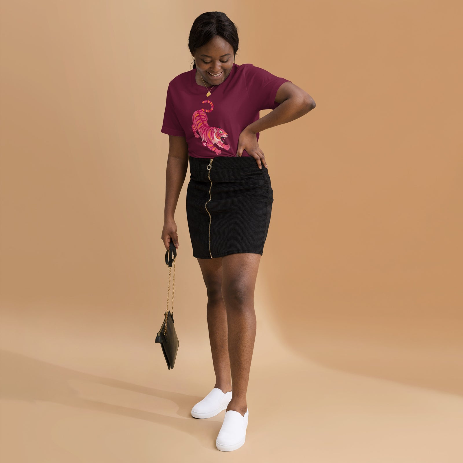 AG - Woman wearing a maroon t-shirt, with a tiger graphic design, on a beige background