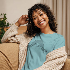 AG - Woman wearing a blue t-shirt with a graphic musical design, sitting on a couch.