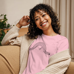AG - Woman wearing a pink t-shirt with a musical graphic design, sitting on a couch.